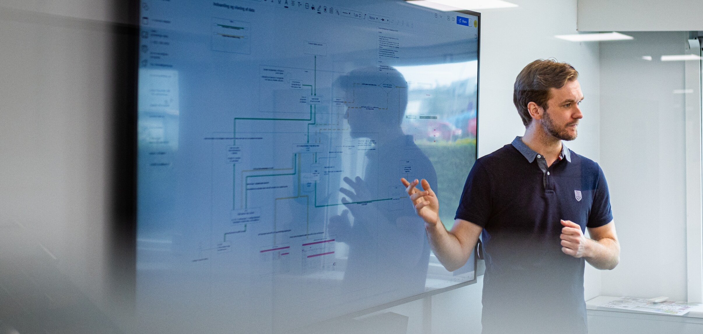 Benjamin står foran skærm og holder oplæg